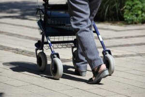 arkinson-Patienten büßen im Verlauf der Erkrankung immer mehr Bewegungsmöglichkeiten ein. Das führt irgendwann zu Schwierigkeiten beim Gehen. An individual walks with a walker along a brick pathway. © Pixabay