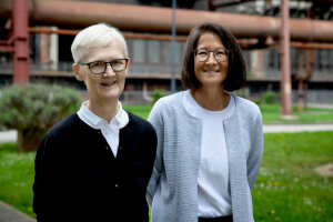 Zwei Frauen, Prof. Dr. Dagmar Timmann und Prof. Dr. Melanie Mark, stehen vor einem Gebäude.