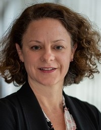 Bild von Prof. Dr. Sigrid Elsenbruch, einer Frau mit lockigem Haar und schwarzem Blazer.